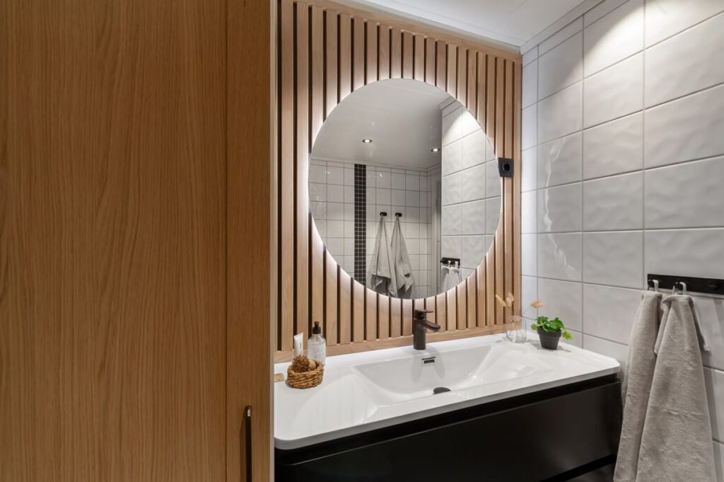 Japandi bathroom with wood paneling and round mirror